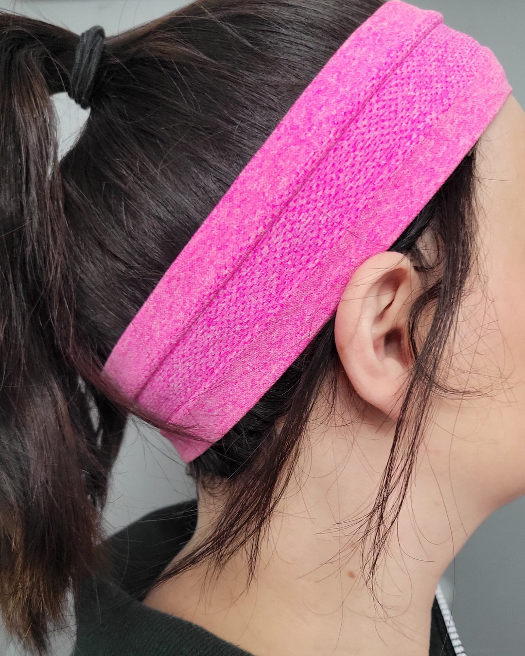 Person wearing a pink headband against a neutral background